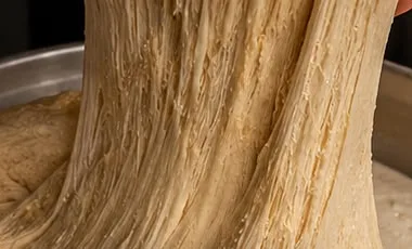Stretchy dough being pulled by hand