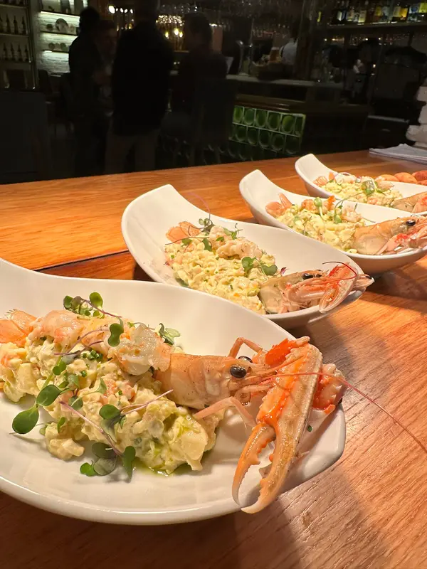 Three plates of seafood ensaladilla topped with a whole langoustine