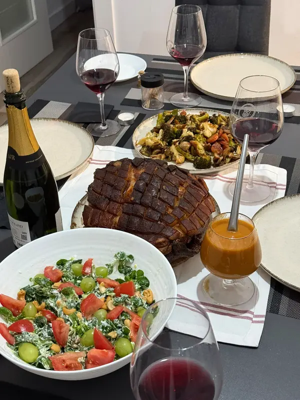 Dinner table with crackling roast pork, salad, roasted vegetables and red wine
