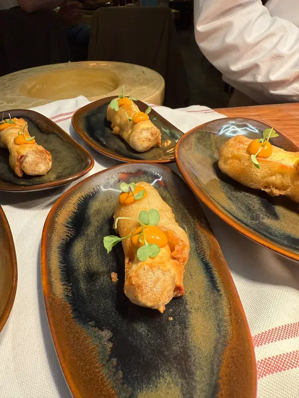 Tempura rolls with dots of orange pepper sauce on ceramic plates