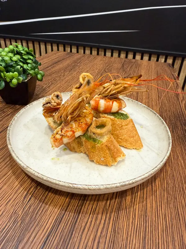 Toasts with green sauce, grilled prawns and fried squid rings
